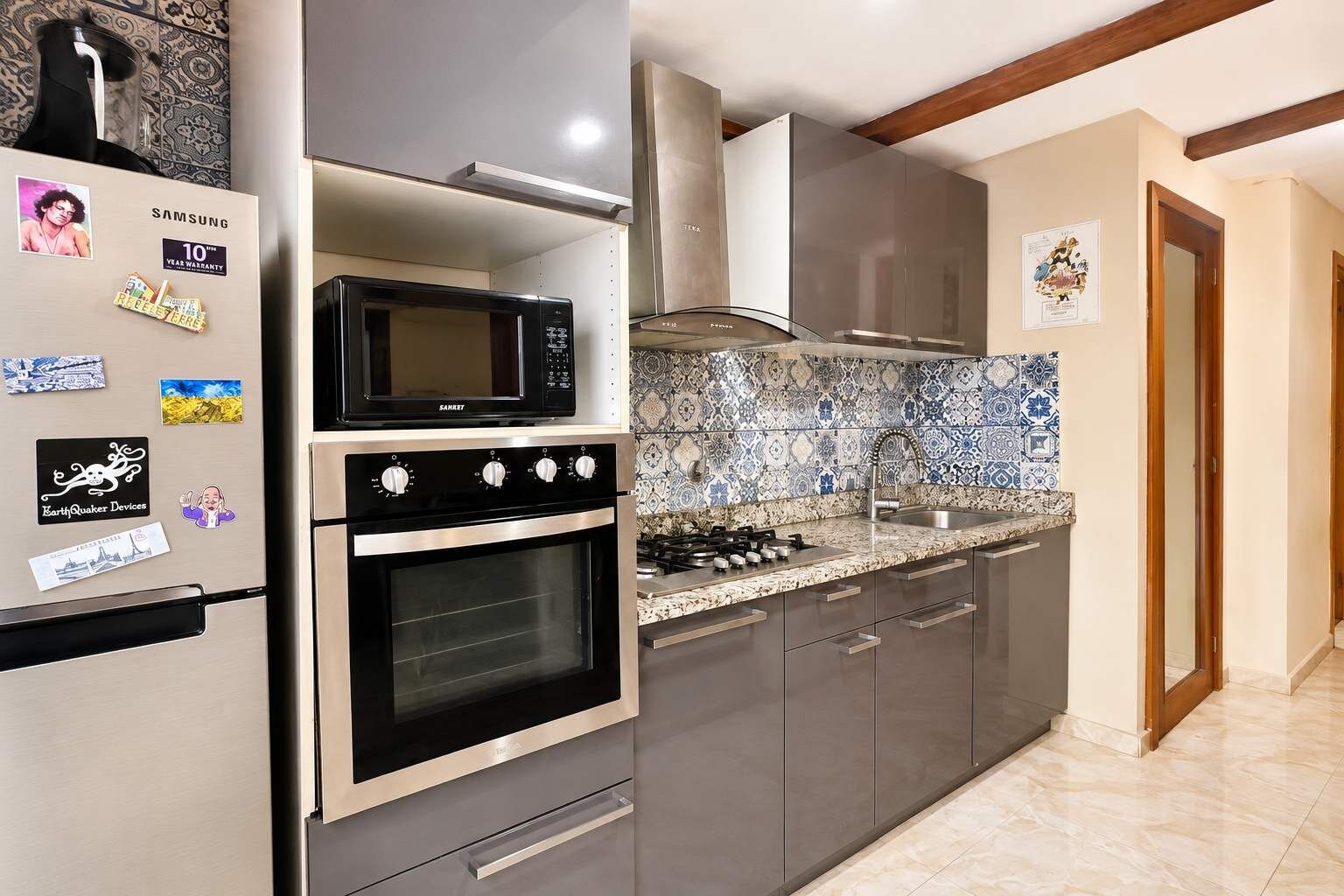 Una cocina con un refrigerador de acero inoxidable, un microondas, un horno y una estufa a gas.