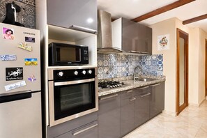 Una cocina con un refrigerador de acero inoxidable, un microondas, un horno y una estufa a gas.