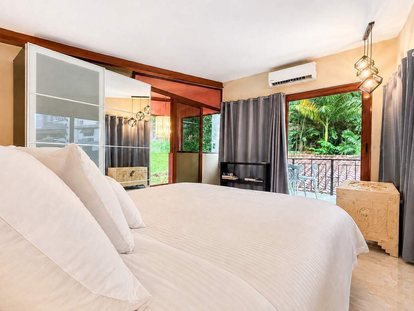 Une chambre avec un grand lit, une télévision et un balcon avec des rideaux.