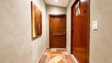 Un pasillo con una puerta de madera, un cuadro en la pared y baldosas con diseño en el suelo.