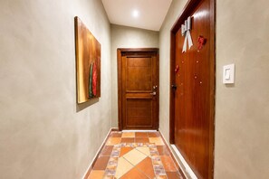 Un pasillo con una puerta de madera, un cuadro en la pared y baldosas con diseño en el suelo.