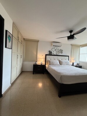 A bedroom with a bed, nightstands, a ceiling fan, and a wall-mounted mirror. - Exclusive Paitilla Apt w/ Free Parking, Steps to (Panamá)