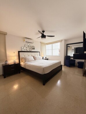A bedroom with a bed, bedside tables, a ceiling fan, a window, and a TV. - Exclusive Paitilla Apt w/ Free Parking, Steps to (Panamá)