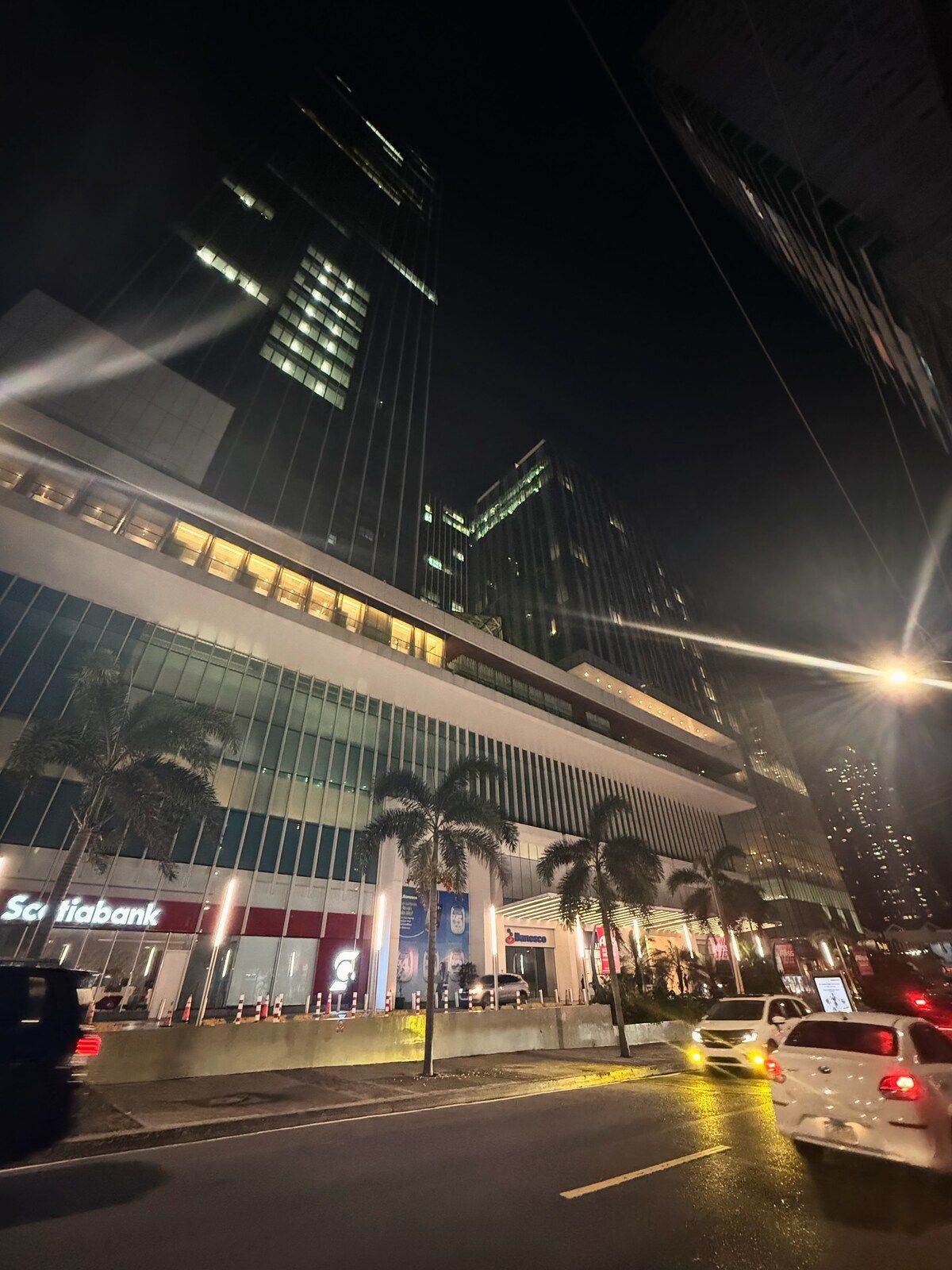 A modern building with a glass facade, a prominent Sci fiabank sign, and palm trees in front.