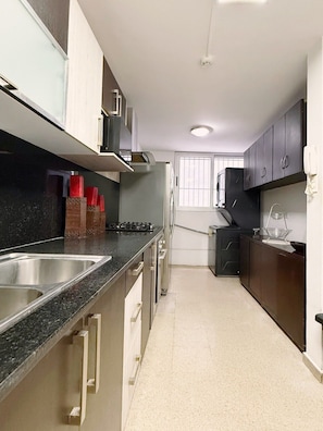 A modern kitchen with a central island, stainless steel appliances, and a window providing natural light. - Exclusive Paitilla Apt w/ Free Parking, Steps to (Panamá)