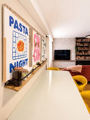 A modern living room with a white table, yellow chairs, a flat-screen TV, and a bookshelf. - Skyline Views Casco Viejo Apt | Historic (Panamá)