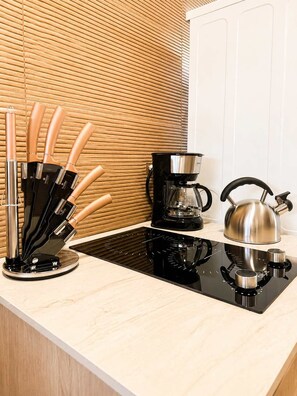 A kitchen counter with a coffee maker, kettle, and knife set. - Skyline Views Casco Viejo Apt | Historic (Panamá)