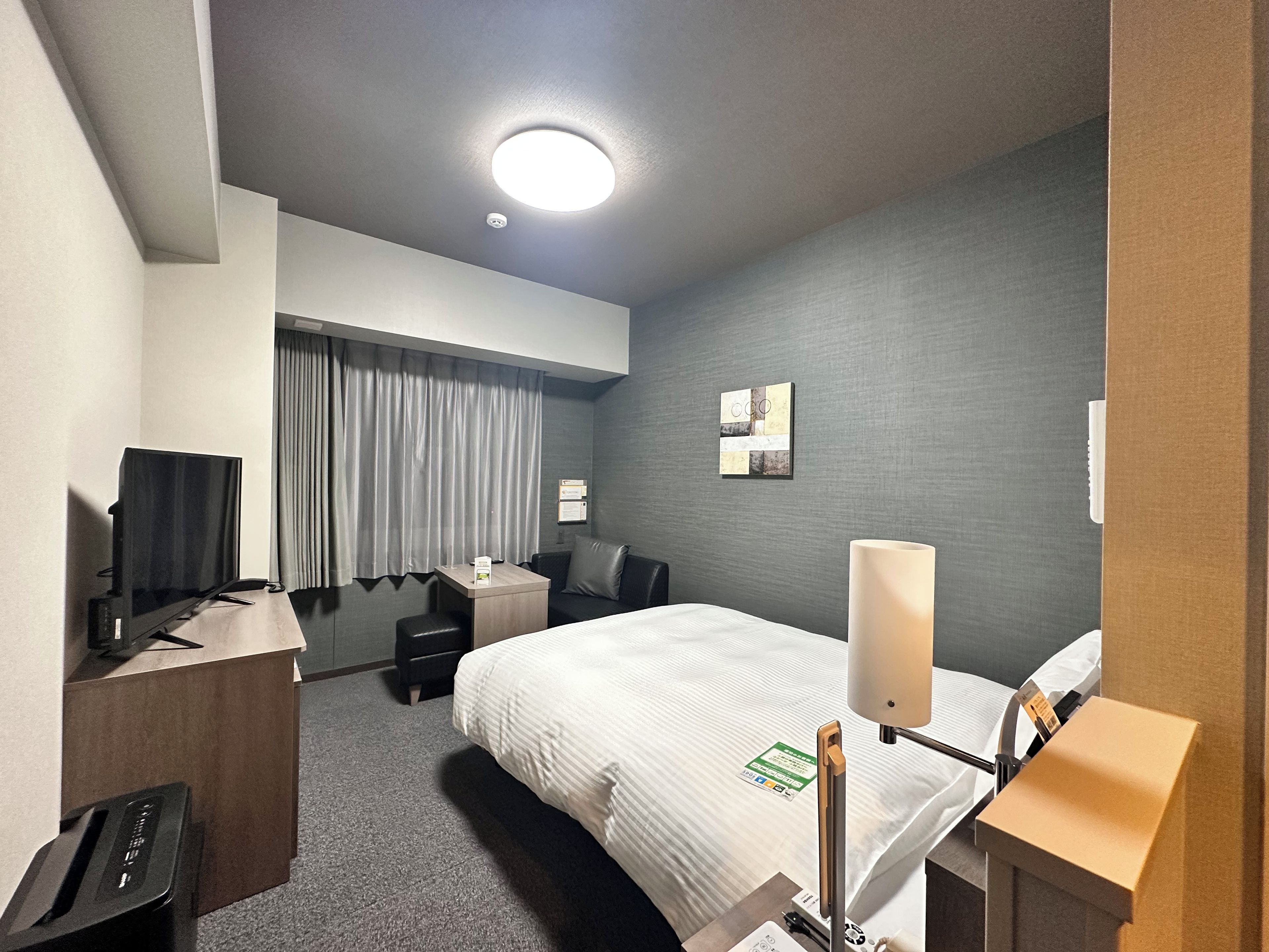 Habitació d'hotel amb llit, escriptori, cadira i televisió de pantalla plana.
