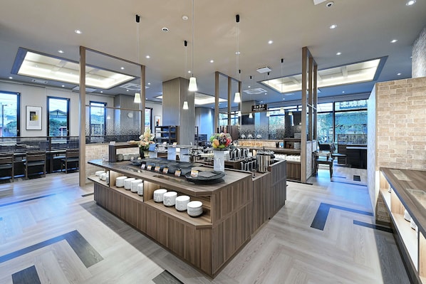 A modern hotel lobby with a central reception desk, seating area, and large windows offering views.