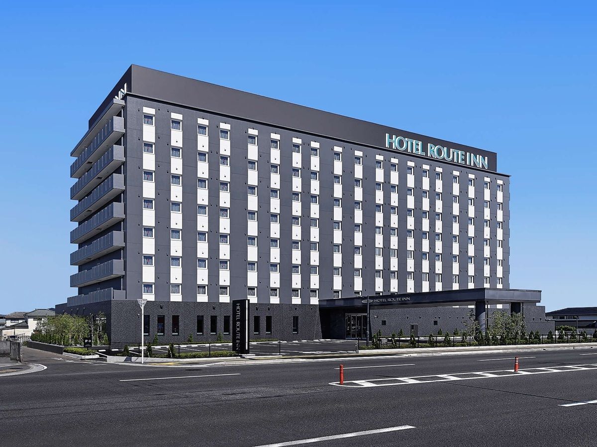 A multi-story hotel building with a modern design, featuring a prominent 'HOTEL ROUTEINN' sign on the facade.