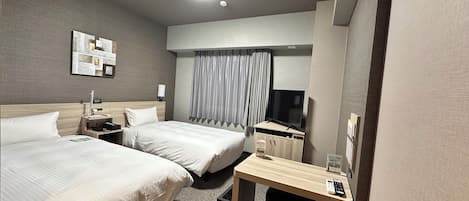 Una habitación de hotel con dos camas, un escritorio, un televisor y una pequeña zona de estar.