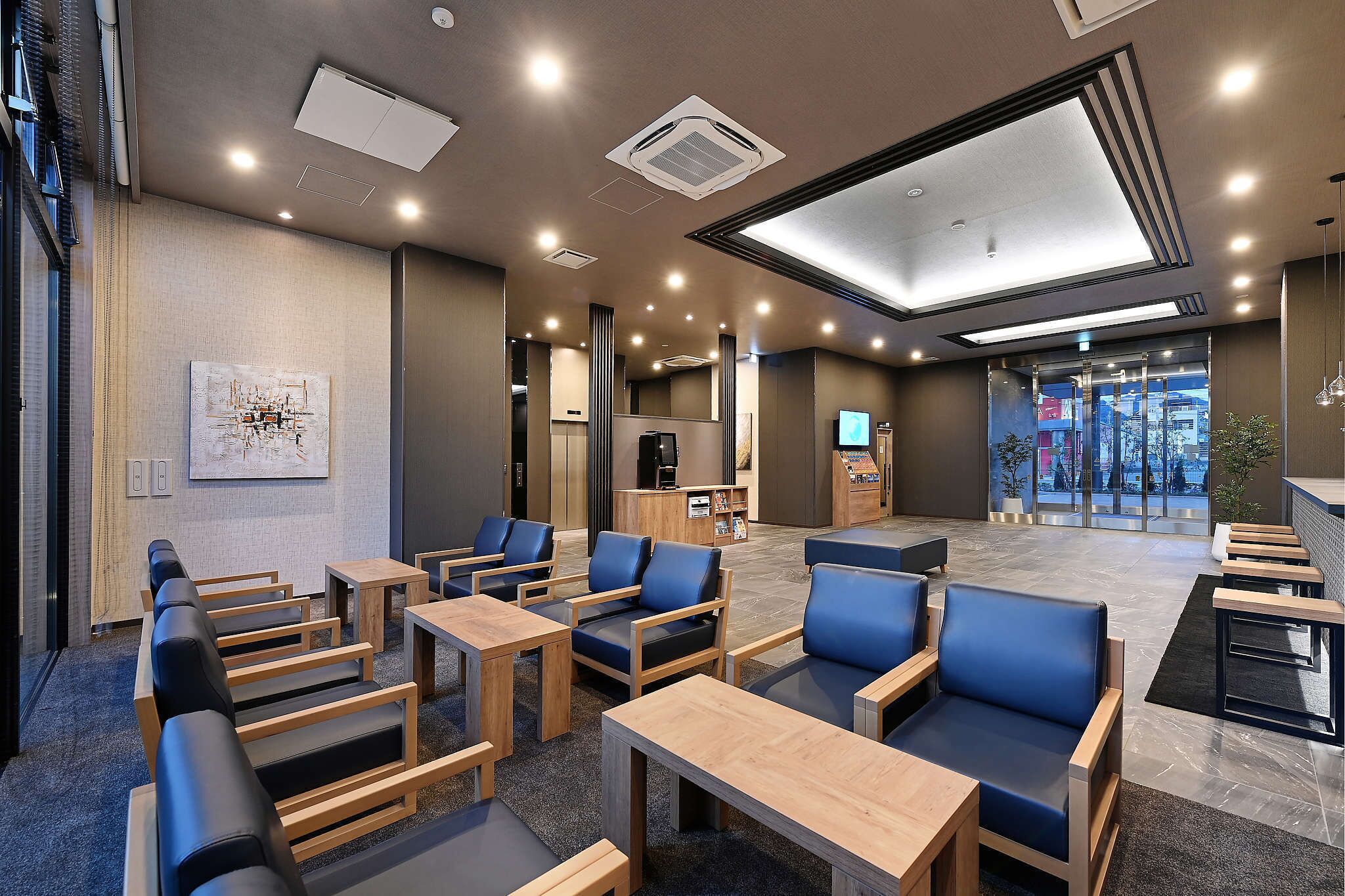 A hotel lobby with seating areas, a reception desk, and a television.