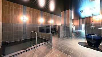 A modern bathroom with a glass-enclosed shower, a large blue basin, and a wall-mounted toilet.