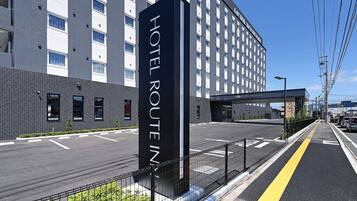 En hotelindgang med et skilt, der viser 'HOTEL ROUTE INN', og en moderne bygning med flere etager og vinduer.