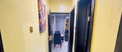 A hallway with a tiled floor, a door on the right, and a painting on the left.