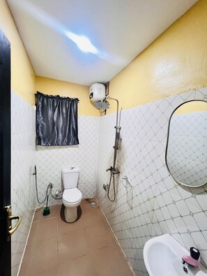 Une petite salle de bain avec des toilettes, une douche et un lavabo.