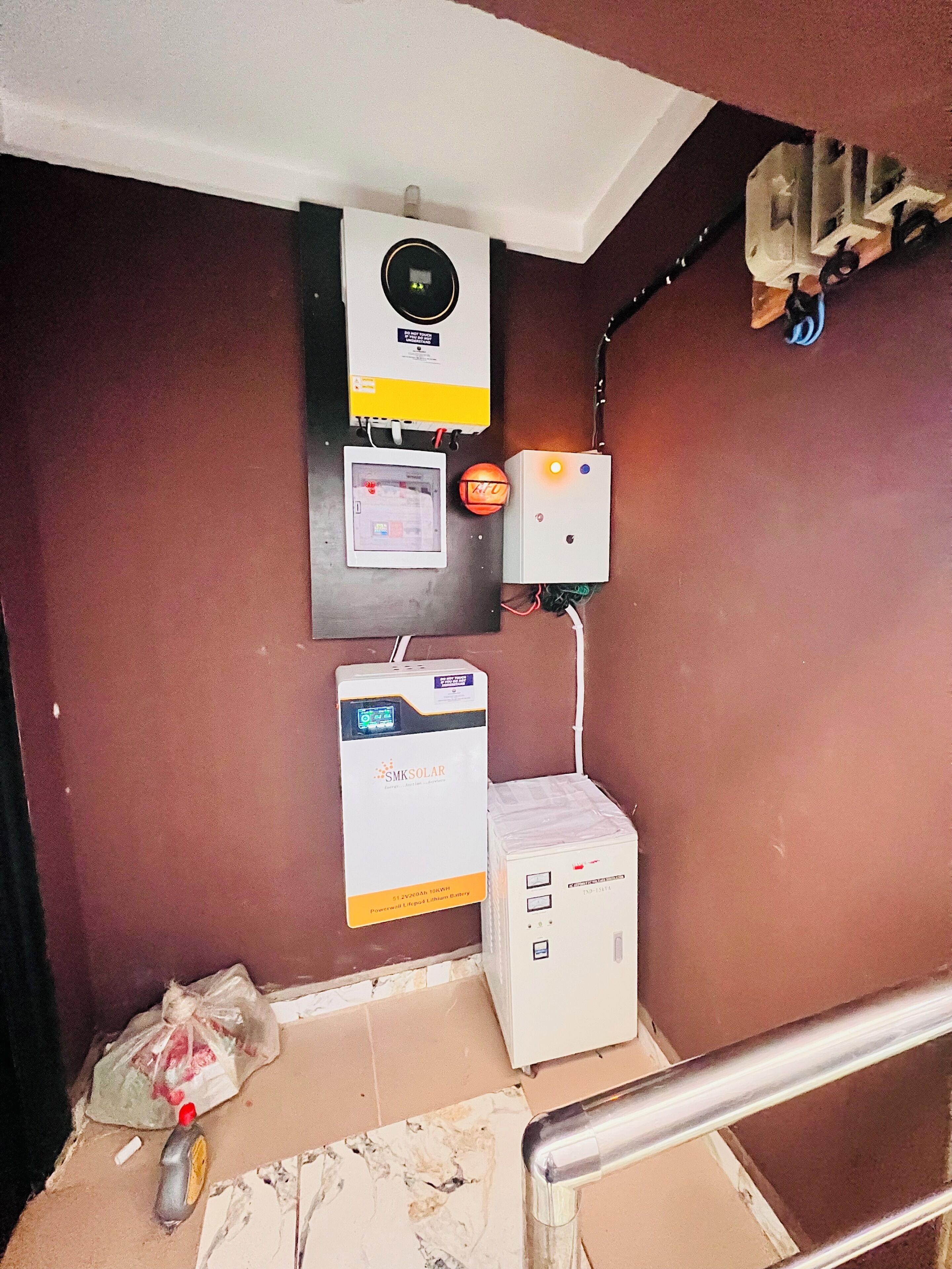 Um cômodo de serviço com aquecedor de água, painel de controle e unidade de armazenamento de bateria.