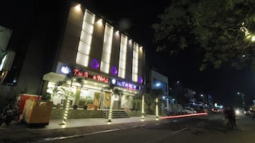 Un hotel con un cartel llamativo, una fachada bien iluminada y vista a la calle de noche.