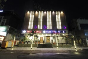 Et hotel med et markant skilt, der viser 'The F's Hotel' og 'BEST MUSIC WORLD', hvilket indikerer et musiktema.