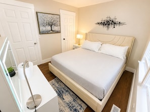 A bedroom with a bed, bedside table, lamp, and a wall art piece.