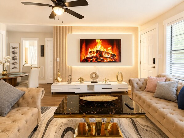 A living room with a fireplace, a ceiling fan, a dining area, and a sofa.