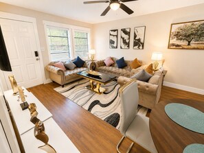 A living room with a sofa set, a coffee table, a rug, and artwork on the walls.