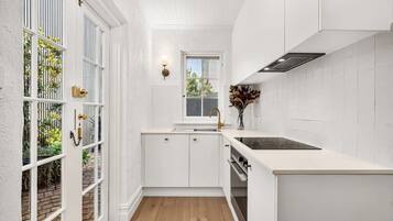 A compact kitchen with white cabinetry, a window, and a view of greenery outside.
