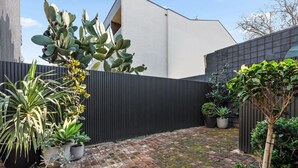 A courtyard with a brick floor, potted plants, and a black fence. - Renovated character cottage, walk to Melbourne St and the city (North Adelaide)