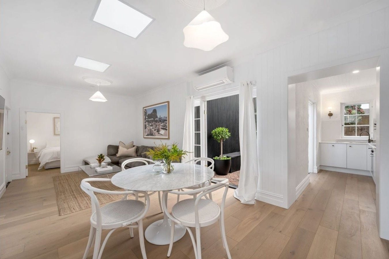 A modern living room with a dining area, a kitchen, and a bedroom.