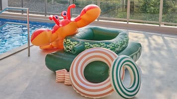 A pool area with inflatable pool toys and a view of the outdoors.