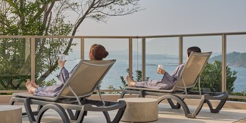 Dos sillones de descanso con vista al mar y las colinas.