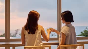 Dos personas sentadas junto a una ventana con vista al atardecer.