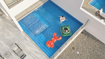 Una piscina en la azotea con vista despejada al cielo, un trampolín y una tumbona.
