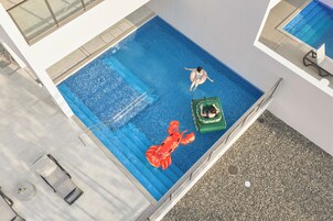 Una piscina en la azotea con vista despejada al cielo, un trampolín y una tumbona.