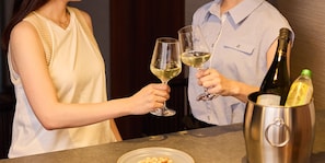 Deux personnes tenant des verres à vin, une bouteille de vin et une bouteille d’huile d’olive sur une table.