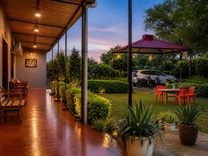 Un espacio al aire libre cubierto con asientos, plantas en macetas y un coche estacionado al fondo.