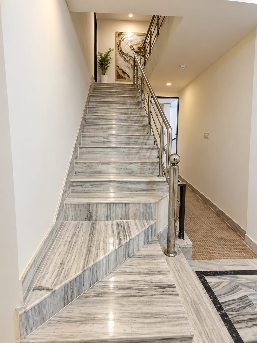 Una escalera de mármol con barandillas de metal que conduce a un rellano.