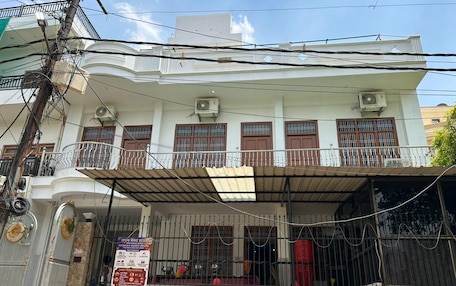A two-story building with a balcony, air conditioning units, and a gated entrance.