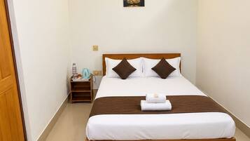 A hotel room with a bed, a ceiling fan, an air conditioning unit, a nightstand, and a wall-mounted artwork.