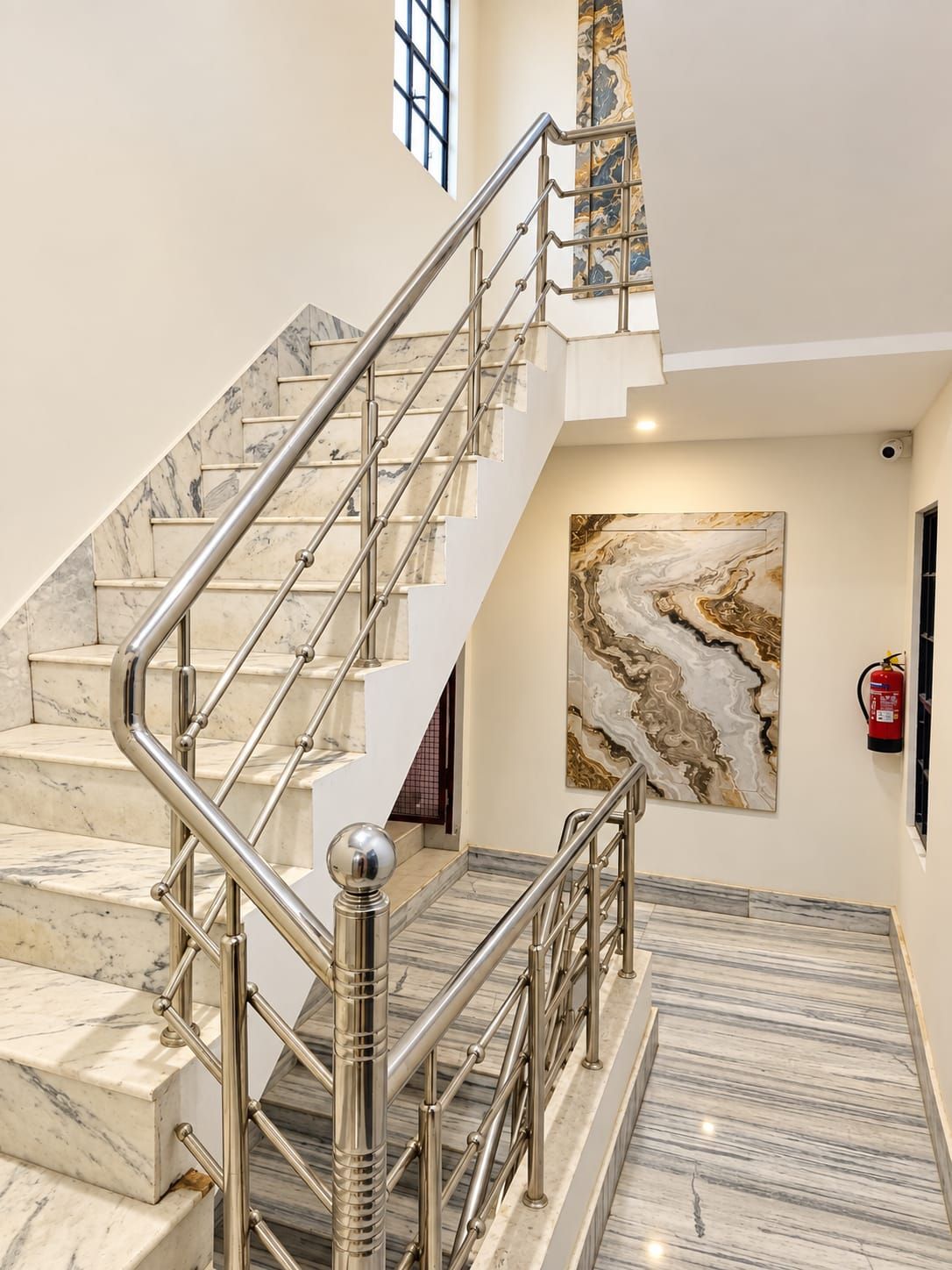 Un escalier en marbre avec des rampes métalliques menant à l’étage supérieur.