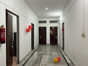 Um corredor com piso de mármore, portas e balões vermelhos.