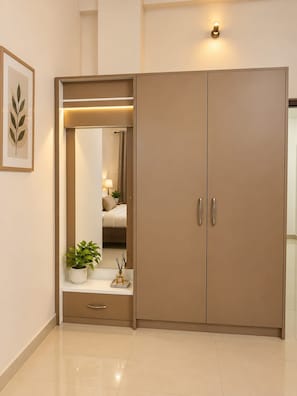 A modern wardrobe with a mirror, a small shelf with a plant, and a wall-mounted light. - Raghav Guest House (Lalpur)