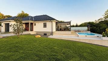 Une maison moderne dotée d’une piscine, d’un patio couvert et d’une pelouse bien entretenue.
