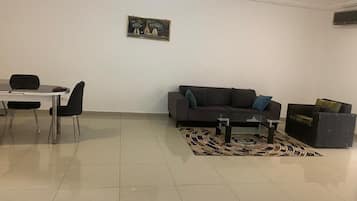 Una sala de estar con sofá, una mesa de centro y un comedor con sillas.