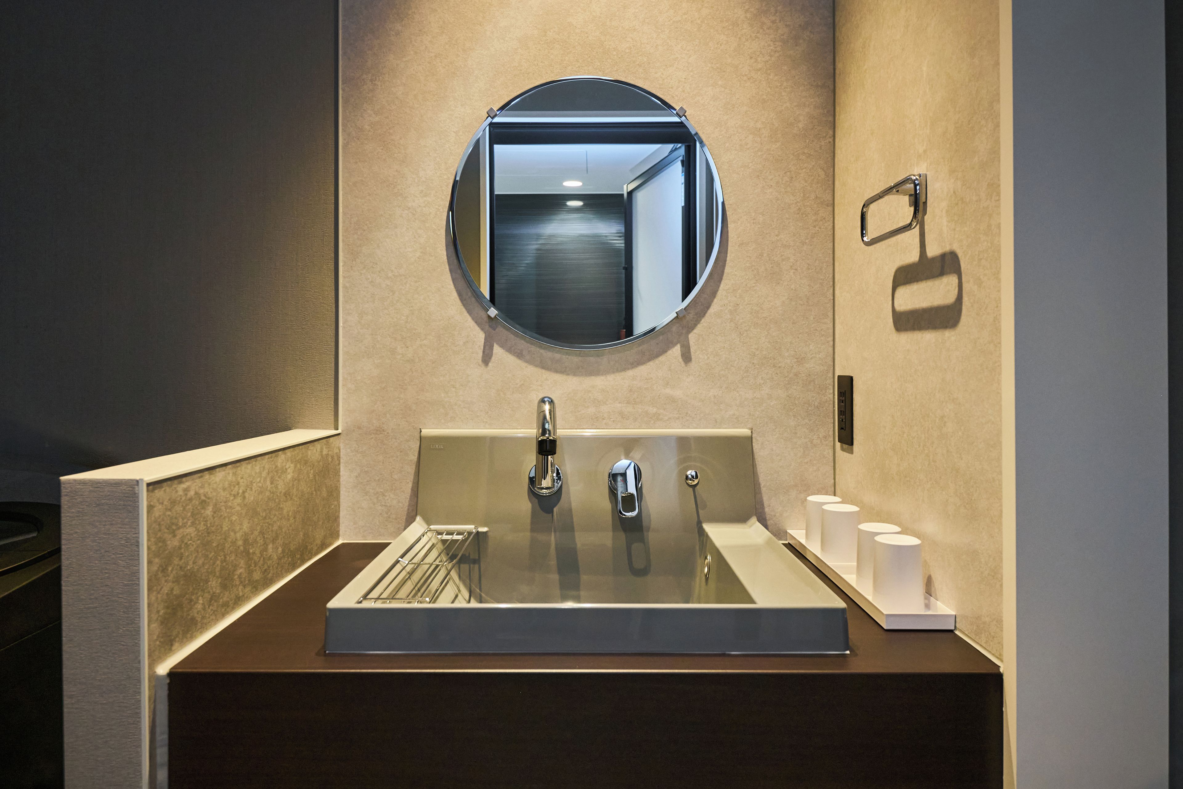 A modern bathroom with a round mirror, a sink, and a towel rack.