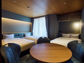 Habitación de hotel con dos camas, una mesa redonda e iluminación empotrada en el techo.