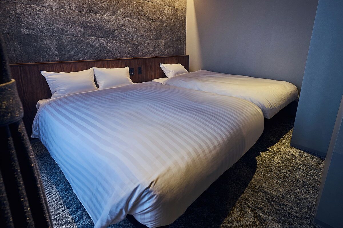 Una habitación de hotel con una cama grande, un cabecero de madera y una pared con textura.