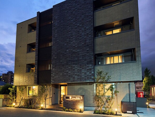 A multi-story building with a modern architectural design, featuring a combination of brick and metal facades, and illuminated windows. - HOTEL SOVA Kumamoto Ekimae (Kumamotoshi)