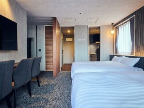 A hotel room with a large bed, a desk with chairs, a flat-screen TV mounted on the wall, and a separate bathroom area. - HOTEL SOVA Kumamoto Ekimae (Kumamotoshi)