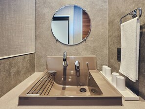 A modern bathroom with a round mirror, two sinks, a towel rack, and a toilet paper holder. - HOTEL SOVA Kumamoto Ekimae (Kumamotoshi)